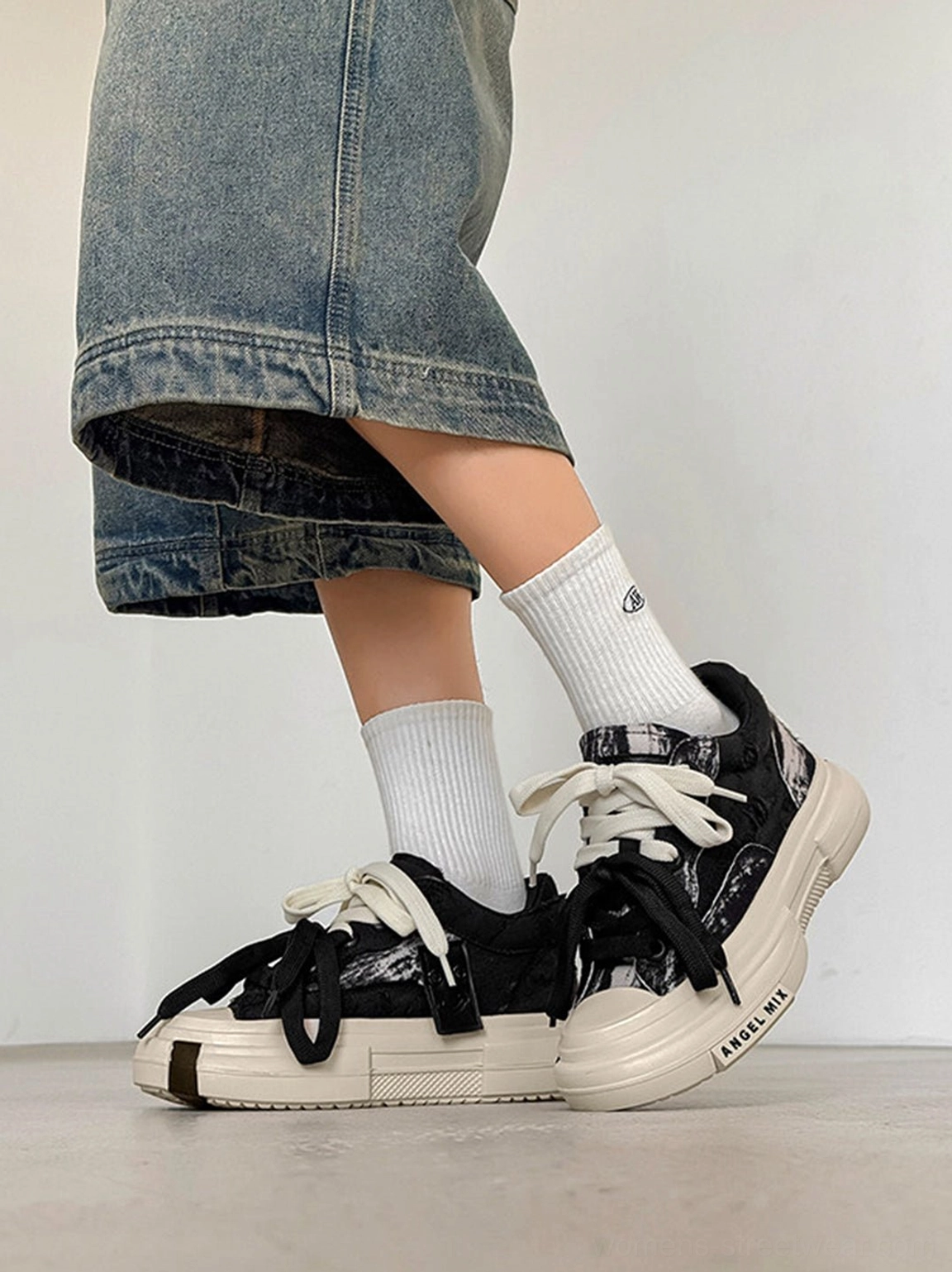 Female model styling black and white canvas platform sneakers with cropped blue denim jeans and white crew socks