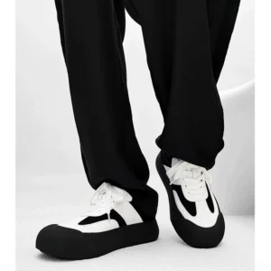 Black and white retro chunky sneakers shown from a low front angle with rounded toe contrast panels and thick platform outsole
