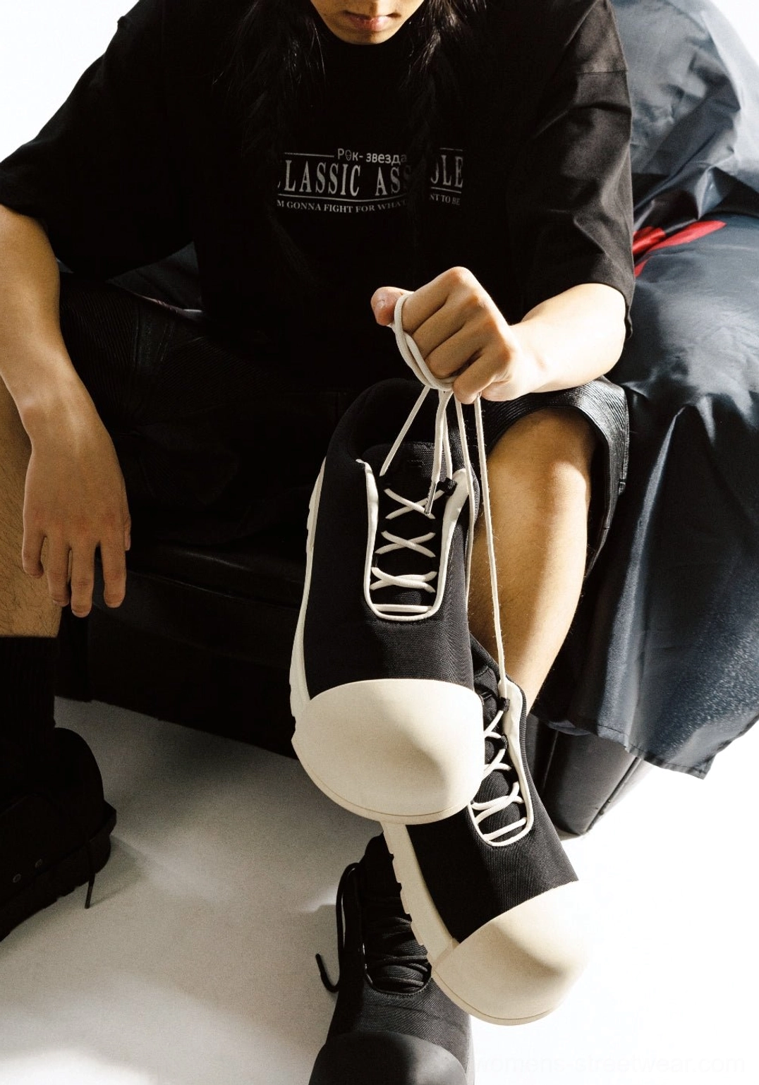 Black and white sculpted toe chunky platform low boots held in hand showing front lace-up and oversized toe details