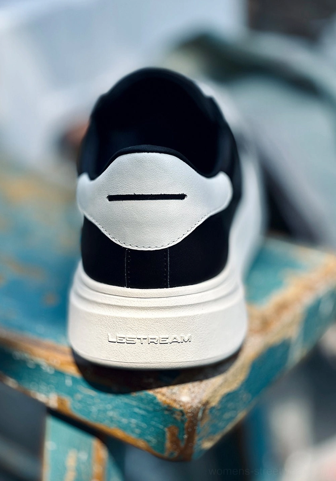 Rear close-up of a black and white shell toe platform sneaker showing the color-blocked heel, white midsole, and textured construction detail