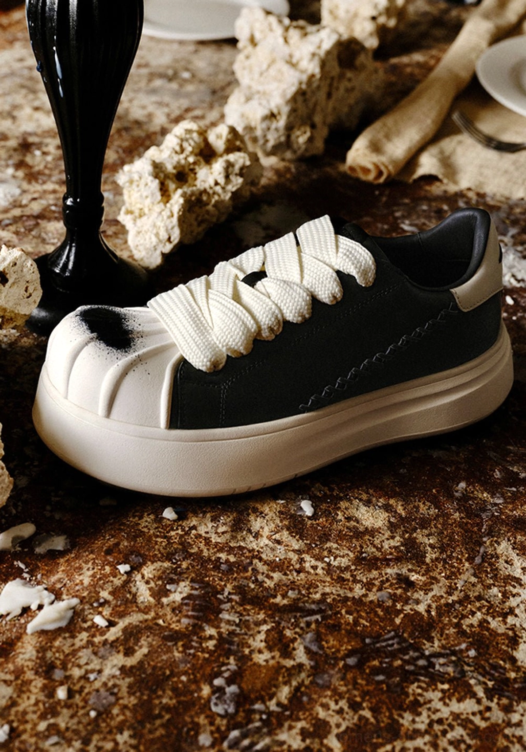 Black and white shell toe platform derby sneakers showcasing the sculpted white toe cap, oversized contrast laces, and rounded low-top profile