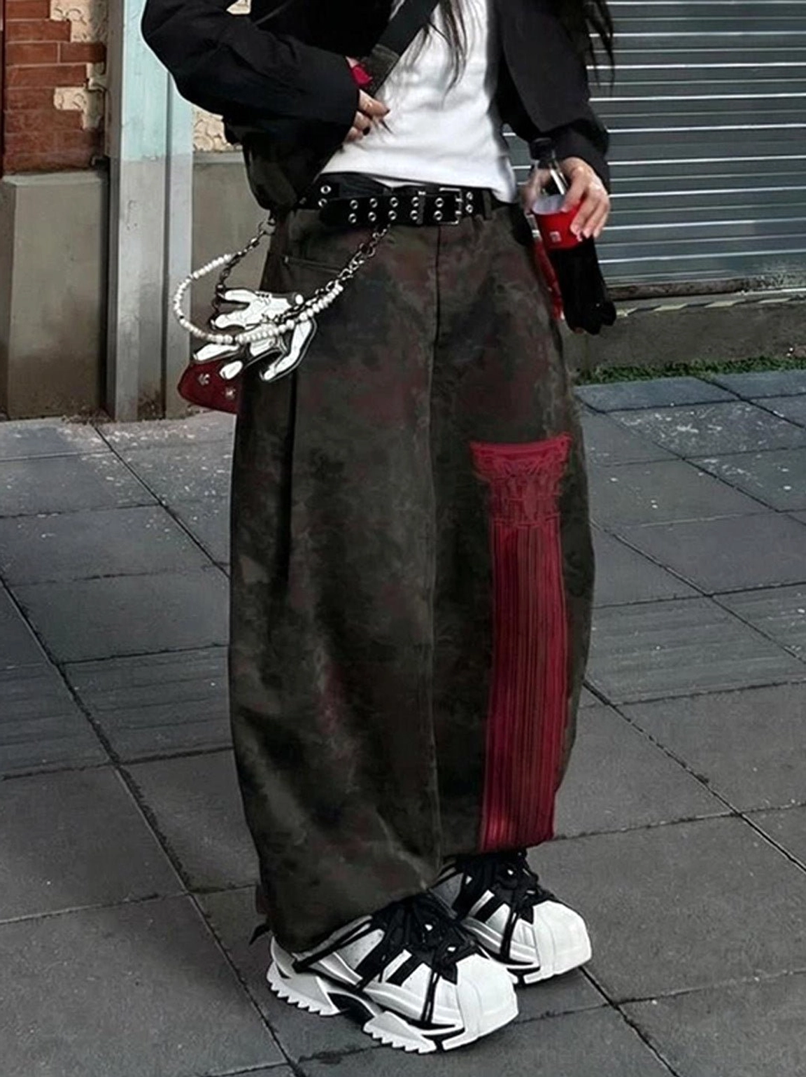 Female streetwear model wearing black and white strapped chunky sneakers with cropped blazer, white tee, and camo cargo pants