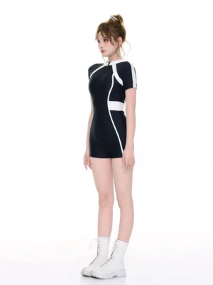 Side view of a fitted black one-piece surf swimsuit with short sleeves, white contrast torso panels, high collar, and fuller-coverage boyleg bottom