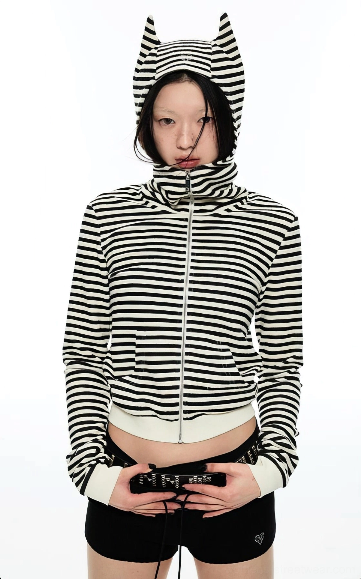 Model wearing a black and white striped cropped cat ear zip hoodie in a full front studio view with ribbed cuffs and waistband
