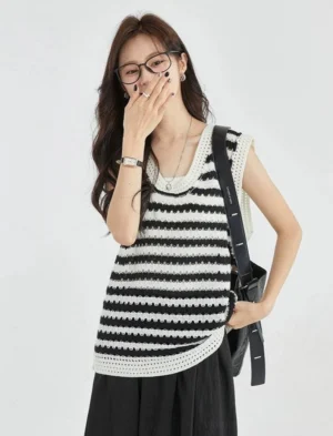 Black and white striped crochet knit sleeveless vest top shown from a front three quarter view with a relaxed fit, U neckline, textured trim, black midi skirt, and crossbody bag