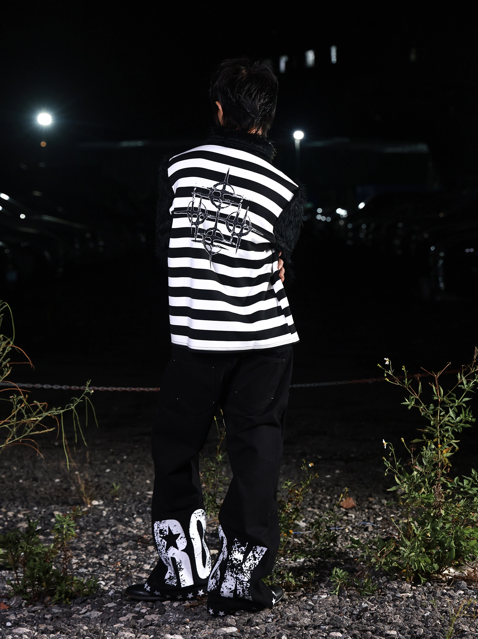Side back view of gothic black and white striped faux fur long sleeve shirt styled with graffiti trousers for an alternative streetwear outfit