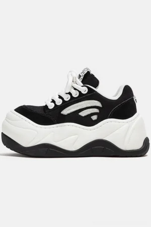 Black and white wave platform chunky sneakers shown in left side profile with lace-up closure, textured upper, contrasting panels, and exaggerated rubber streetwear sole