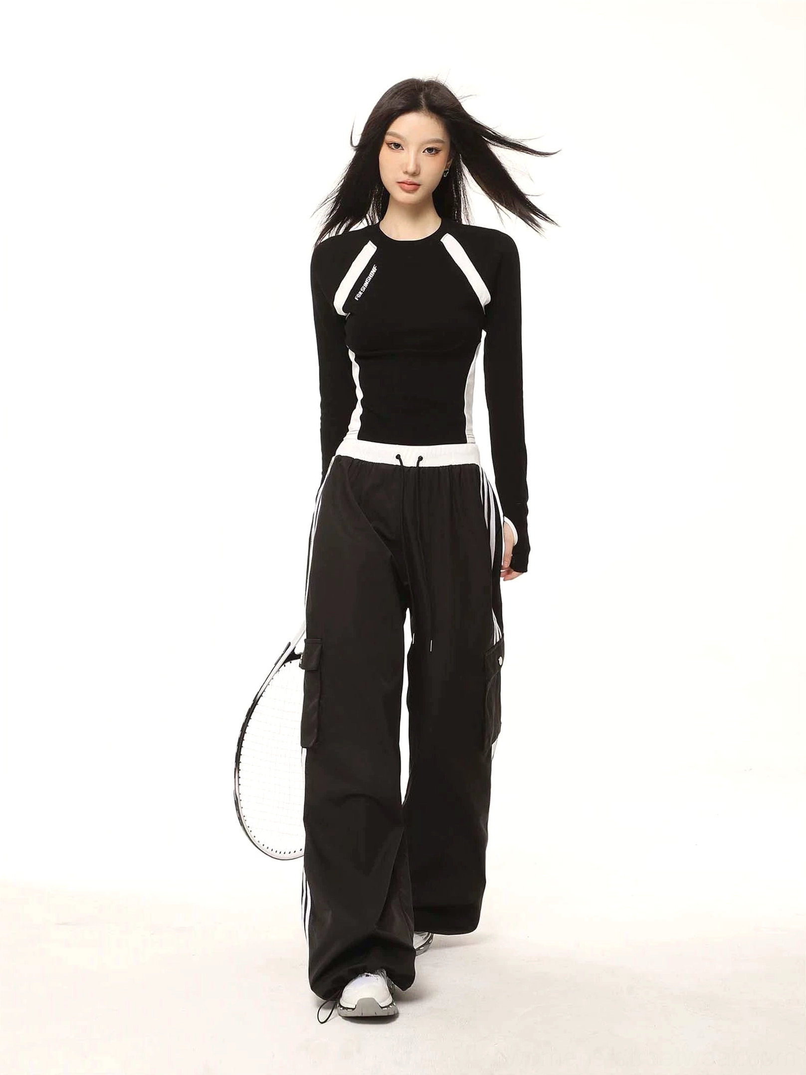 Black and white Y2K contrast raglan cropped long sleeve top in a full-body sporty streetwear outfit with tennis racket
