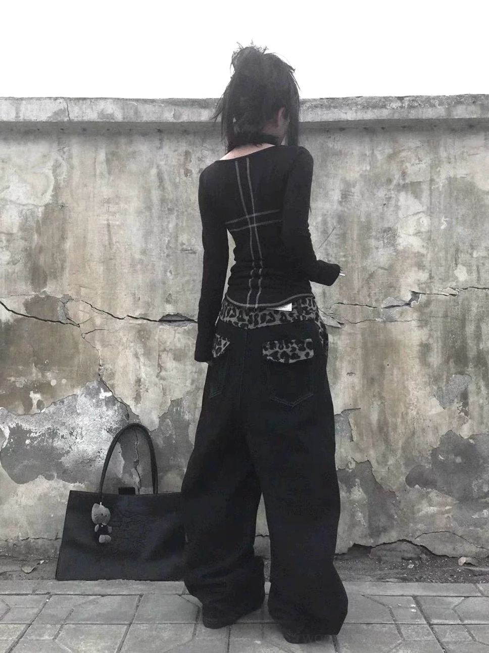 Back view of black wide leg baggy jeans with leopard print back pocket details and oversized streetwear silhouette