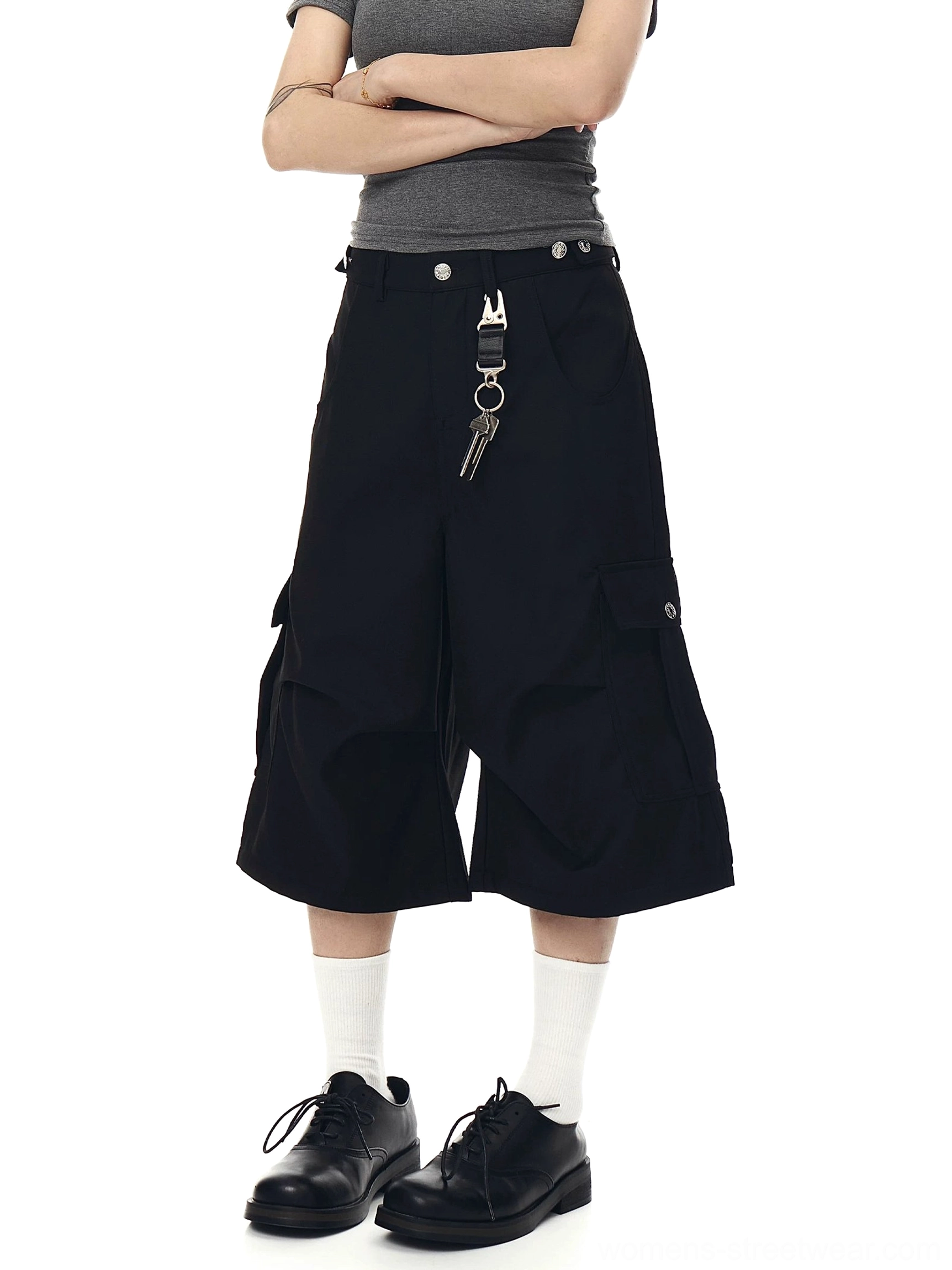 Front styling view of black wide-leg cargo culotte shorts with cropped proportions, side utility pockets, and Korean fashion details