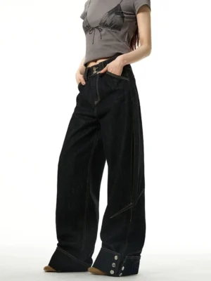Three-quarter front view of black wide-leg cuffed jeans with buttoned hems and contrast stitching styled with a gray cropped graphic tee