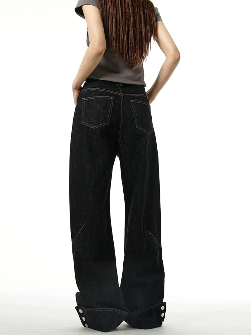 Rear view of black wide-leg denim jeans showing back patch pockets, contrast stitching, and secured rolled hems