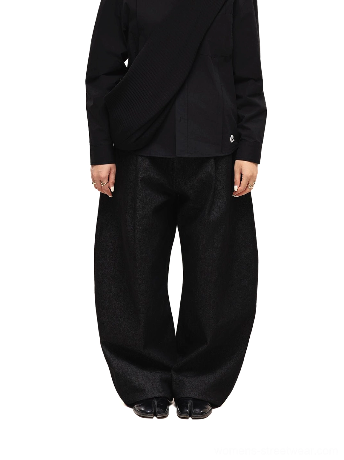 Back full-body styling view of black wide-leg denim jeans worn with an all-black top and polished leather shoes