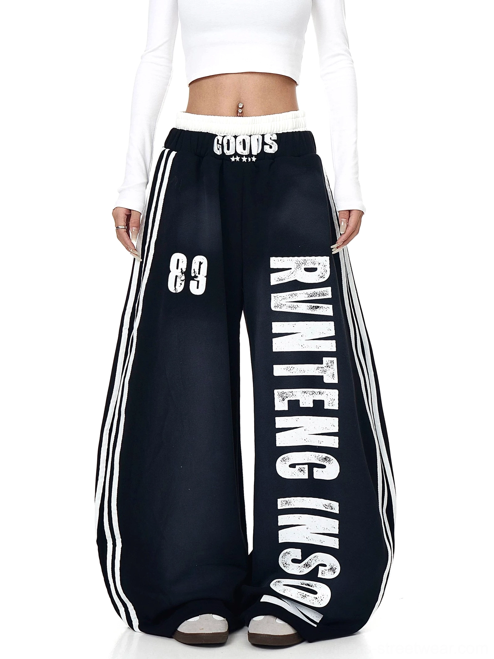 Front view of black wide-leg graphic sweatpants with white vertical varsity print, 89 motif, elastic waist, and track-inspired stripes