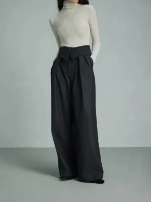 Black high-waist wide-leg tailored streetwear trousers styled with a cream turtleneck in a minimalist studio