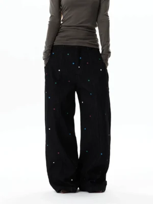 Back view of black oversized wide-leg jeans covered with colorful rhinestone details and classic denim button fly waistband