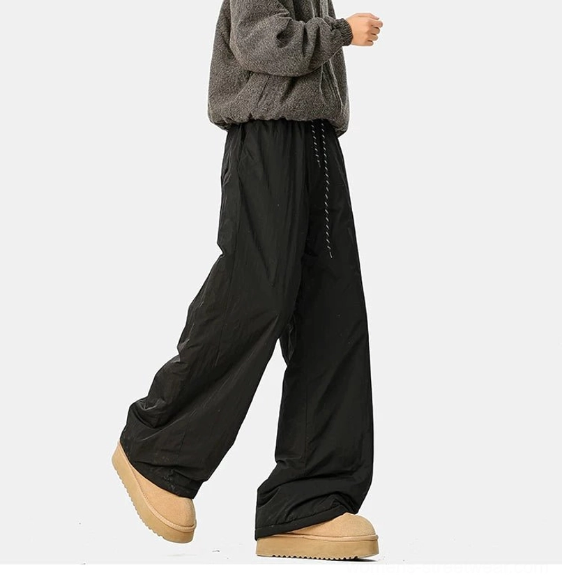 Black wide-leg streetwear pants with contrast drawstring, loose crinkled fabric, and cozy winter styling