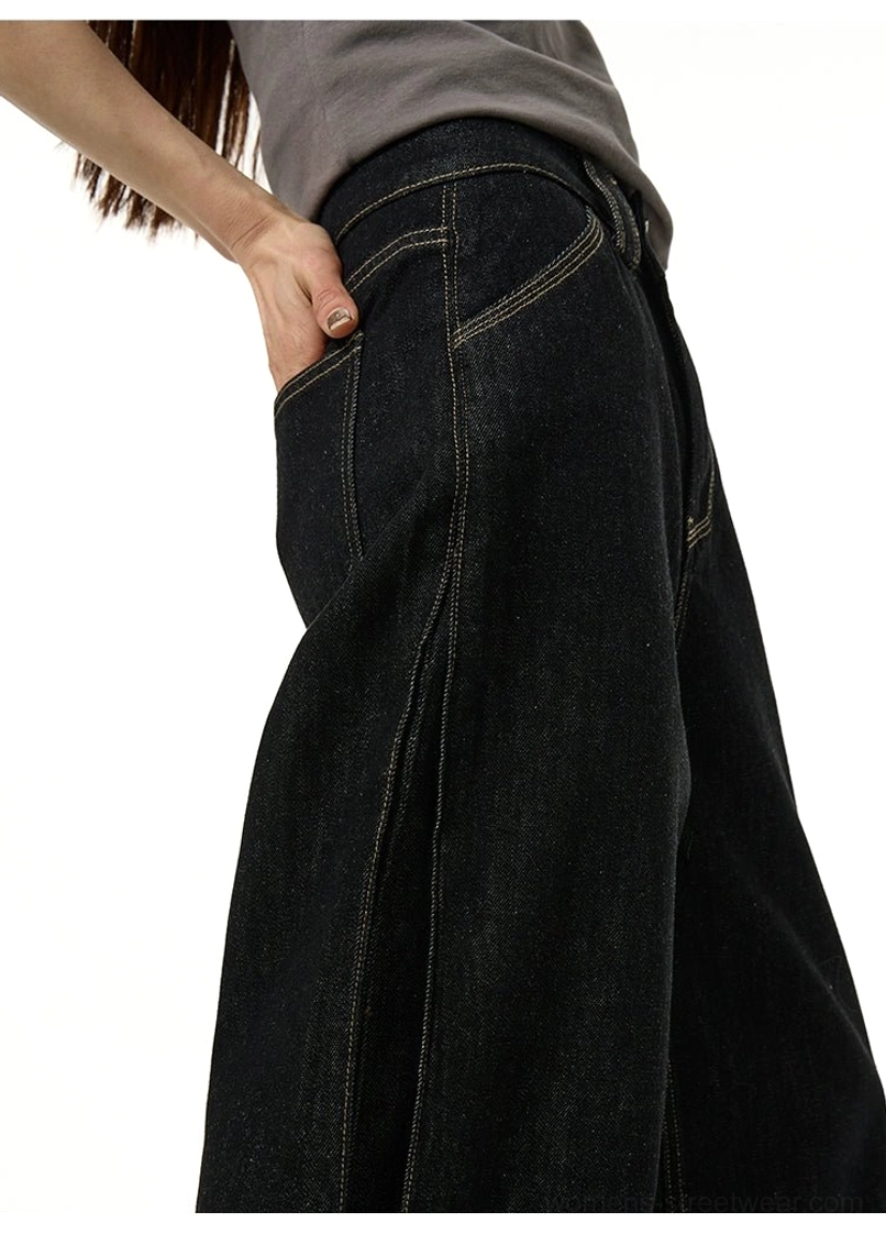 Side three-quarter view of relaxed black wide-leg streetwear pants with curved seams and contrast topstitching