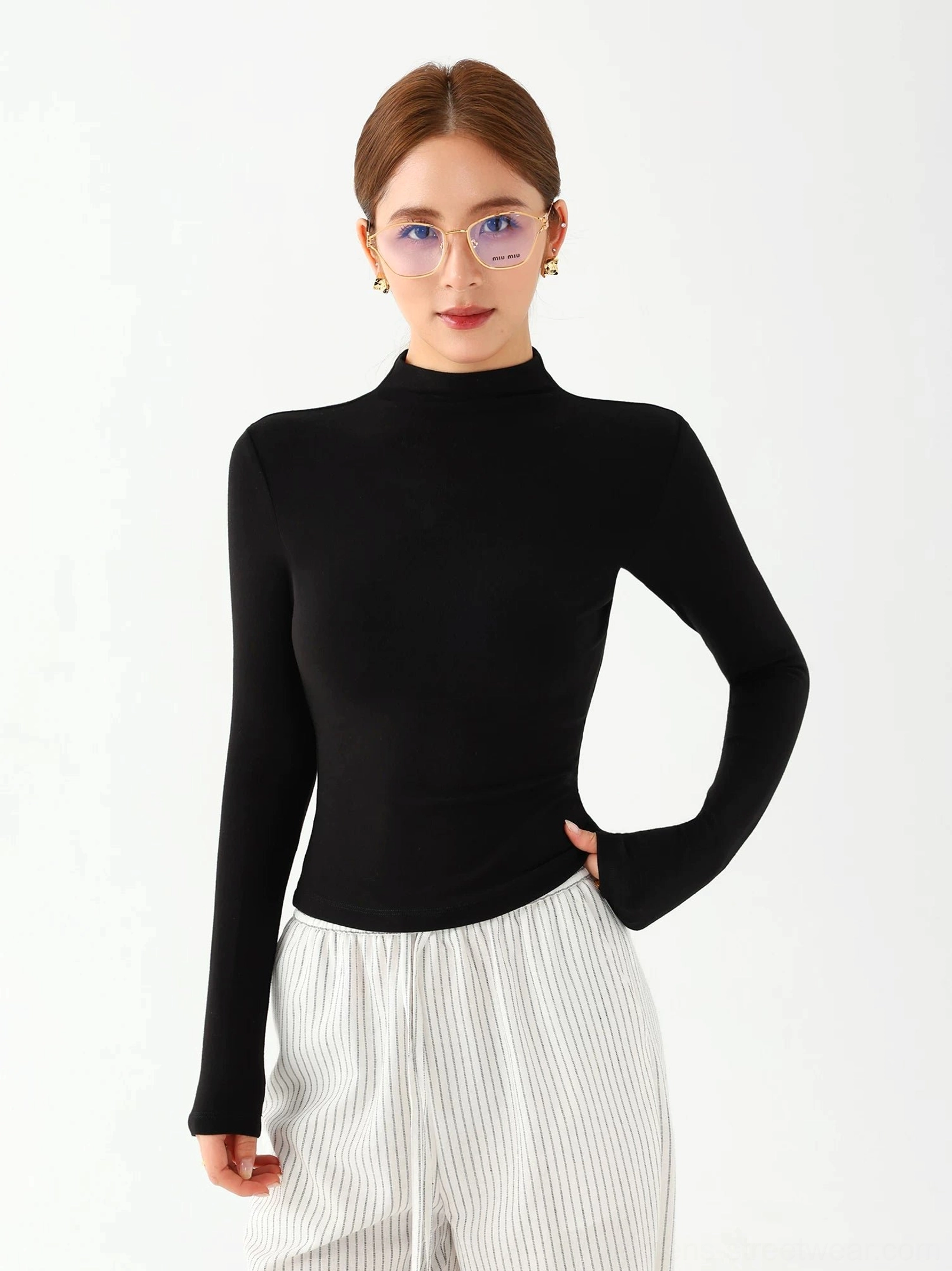 Black women's fitted mock neck long sleeve top paired with a white striped wide leg skirt
