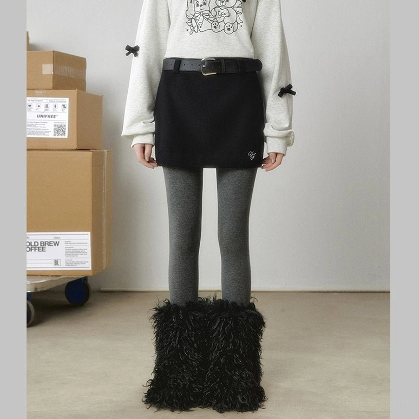 Black wool-look mini skirt styled with grey tights and fuzzy tall boots for a dark Y2K streetwear outfit