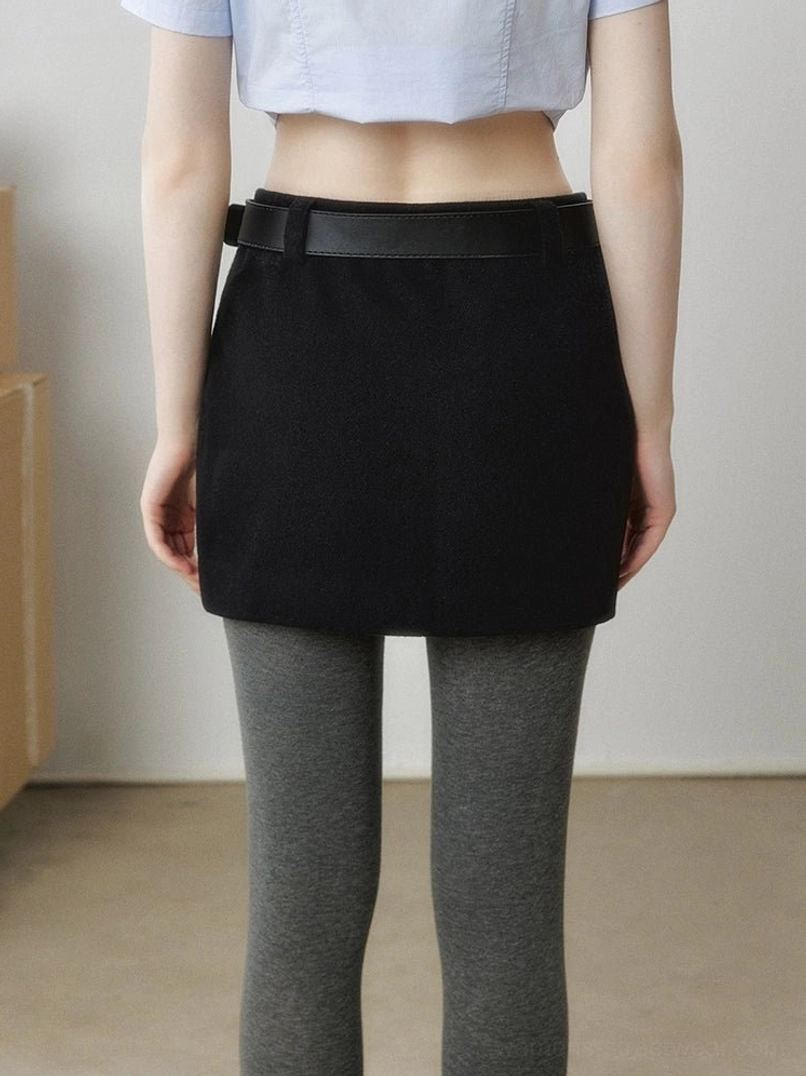 Black wool-look mini skirt front close-up showing slim A-line silhouette, textured fabric, wide black waistband, and tailored waist detail