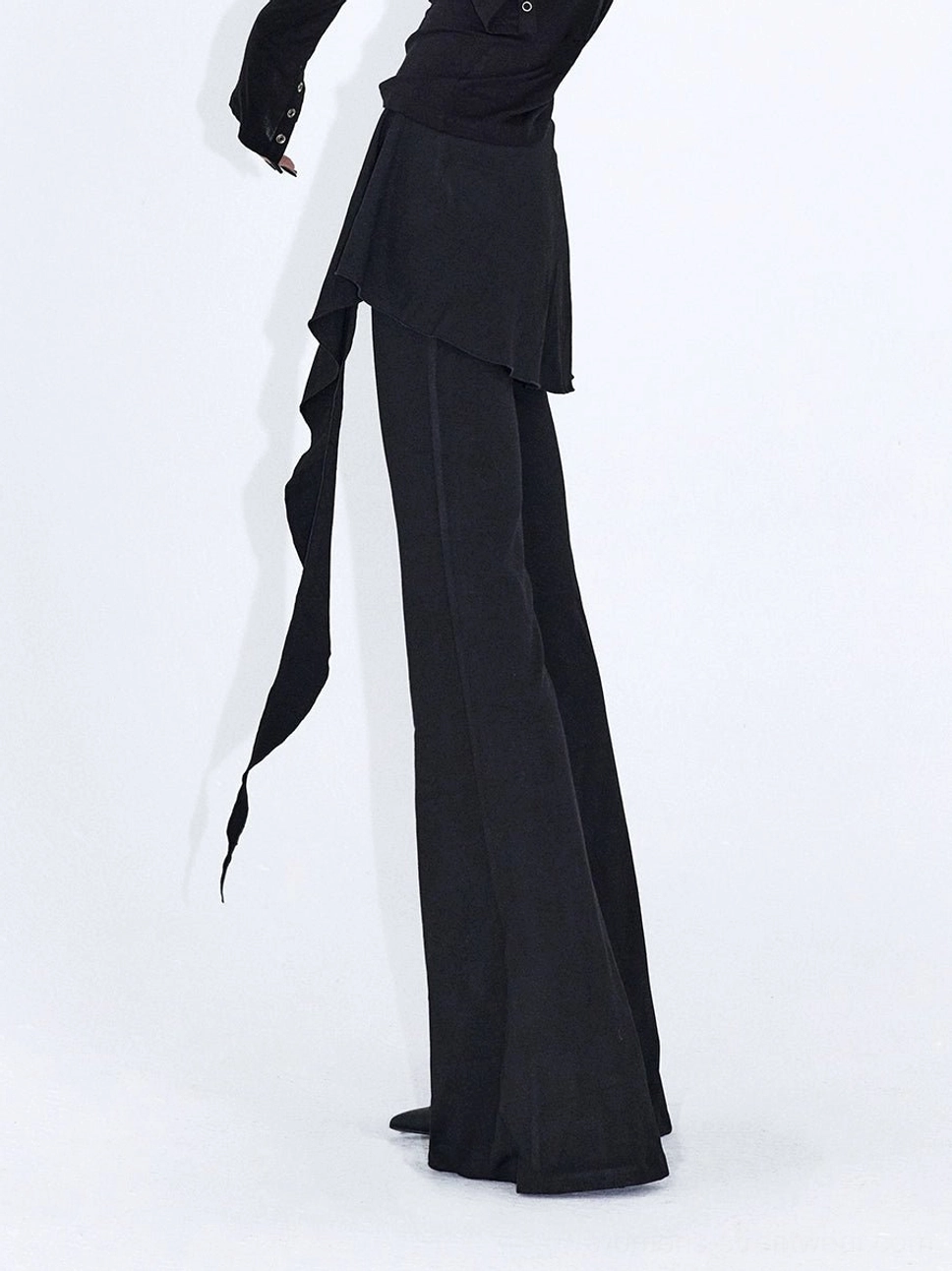 Solid black wrap drape flare streetwear pants shown from the side with a long asymmetric waist tie and matte finish