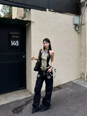 Full front view of a female model wearing black gothic Y2K flare jeans with graphic front pockets and multi-button fly closure