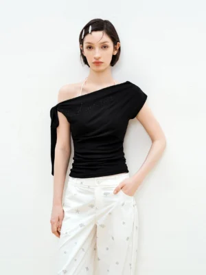 Black Y2K rhinestone asymmetric one-shoulder fitted top styled with white star print wide-leg pants in a studio