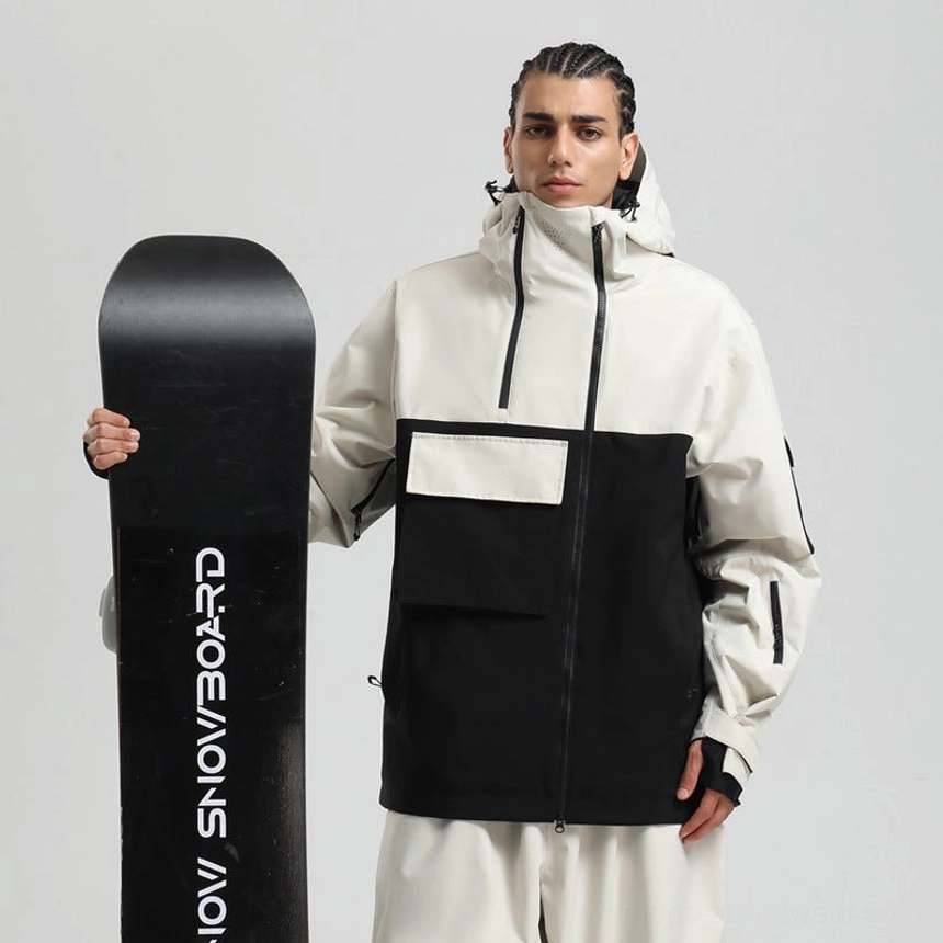 White and black block panel tech snowboard jacket worn with a snowboard in a streetwear studio look