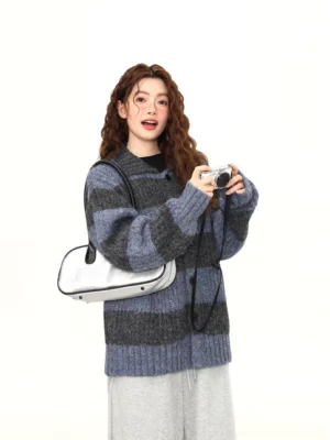 Blue and charcoal fuzzy striped cardigan shown in a three-quarter side view with relaxed shoulders, textured knit, silver underarm bag, and vintage camera