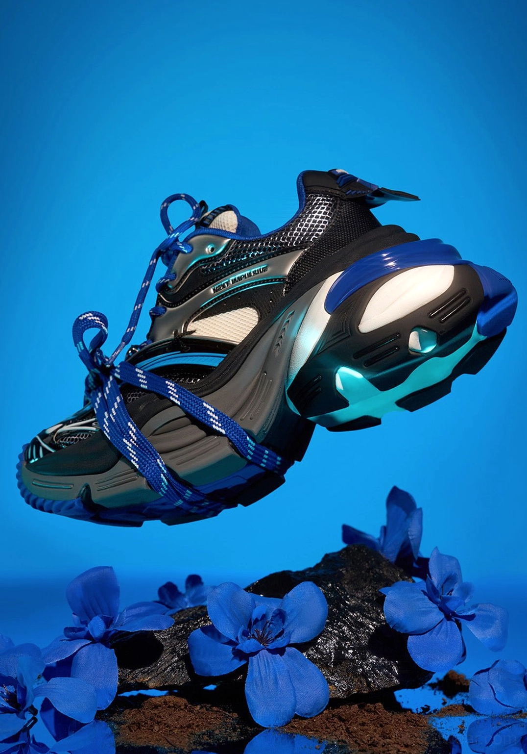Blue chunky platform dad sneaker shown in a dynamic three-quarter side view with layered midsole construction, mixed upper textures, and blue sole accents