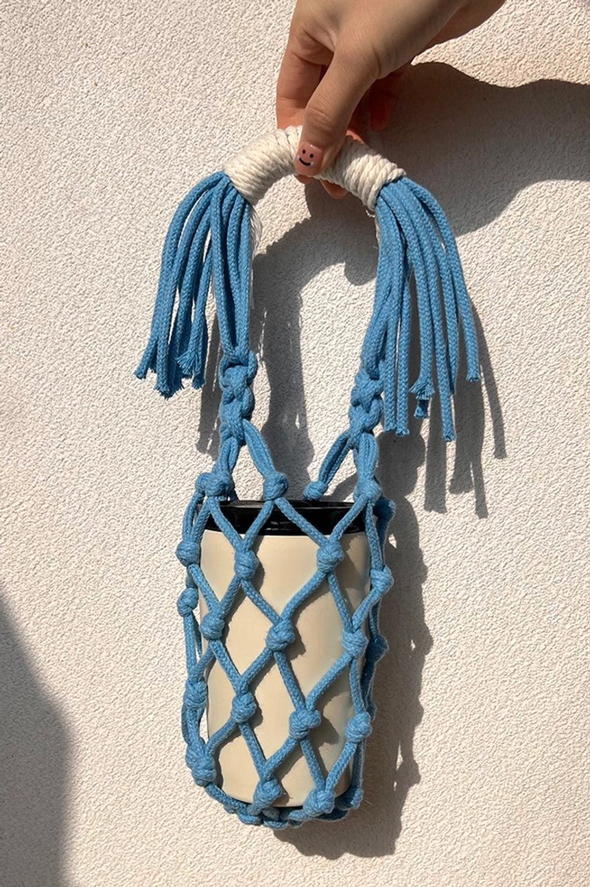 Blue cotton macrame water bottle carrier accessory with hand-knotted rope net, lightweight handle, and relaxed boho streetwear style