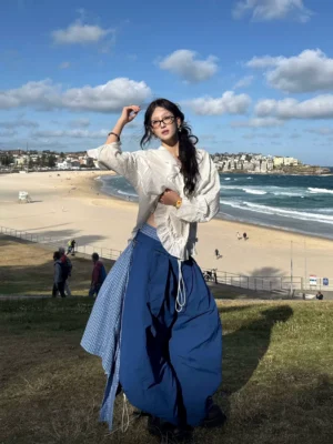 Blue oversized detachable layered balloon parachute cargo pants with a blue plaid wrap overlay styled on a model outdoors, showing the adjustable drawstring waist and wide-leg silhouette