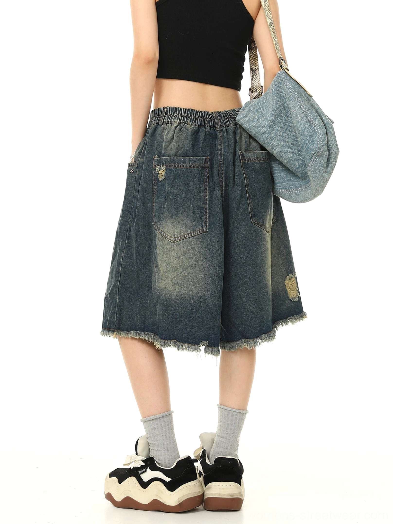 Back view of blue distressed denim Bermuda shorts showing elasticated back waistband, dual patch pockets, faded wash, and frayed hems