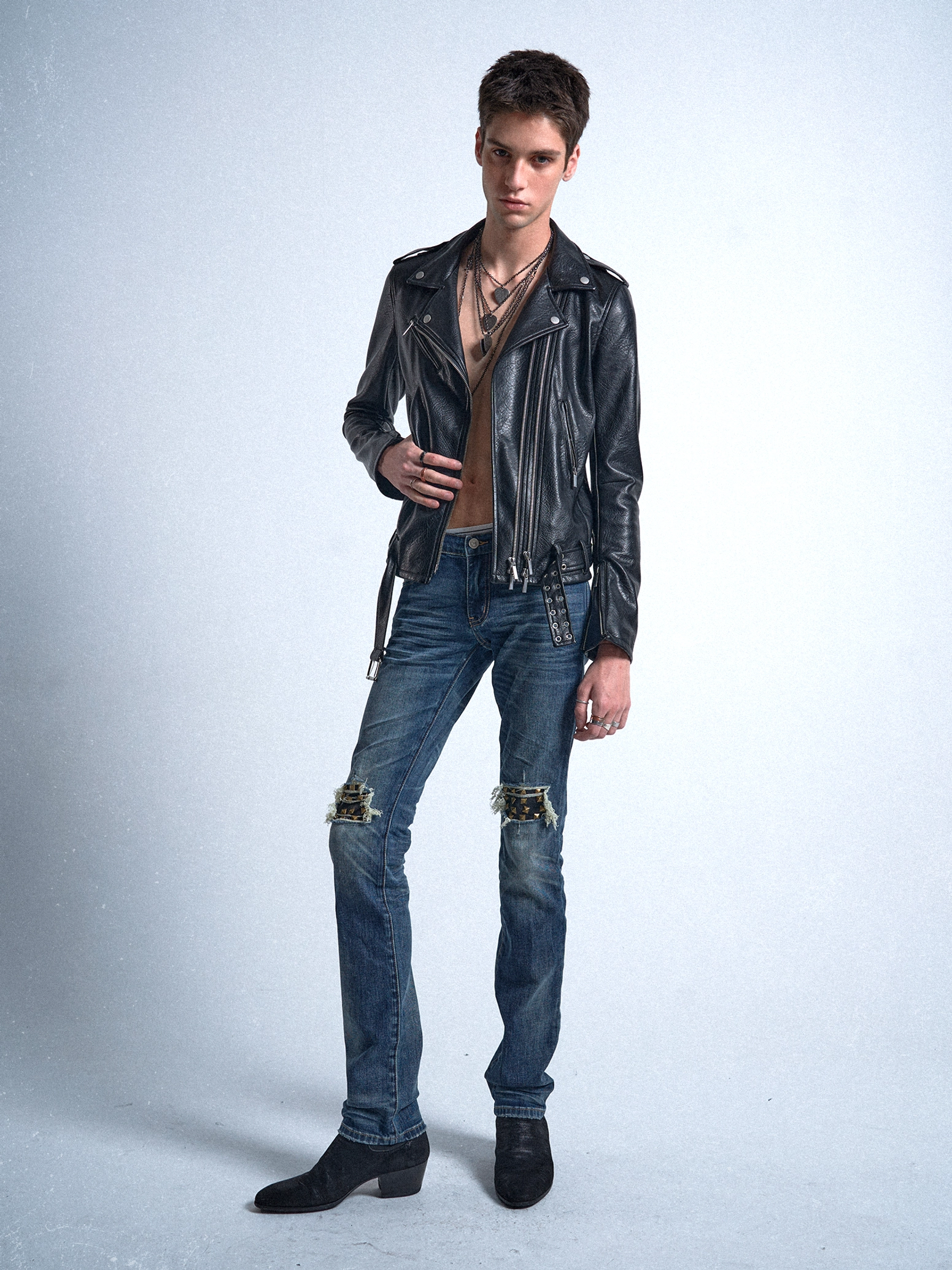 Blue distressed slim denim jeans with faded thighs and reinforced knee details paired with a black leather biker jacket and boots