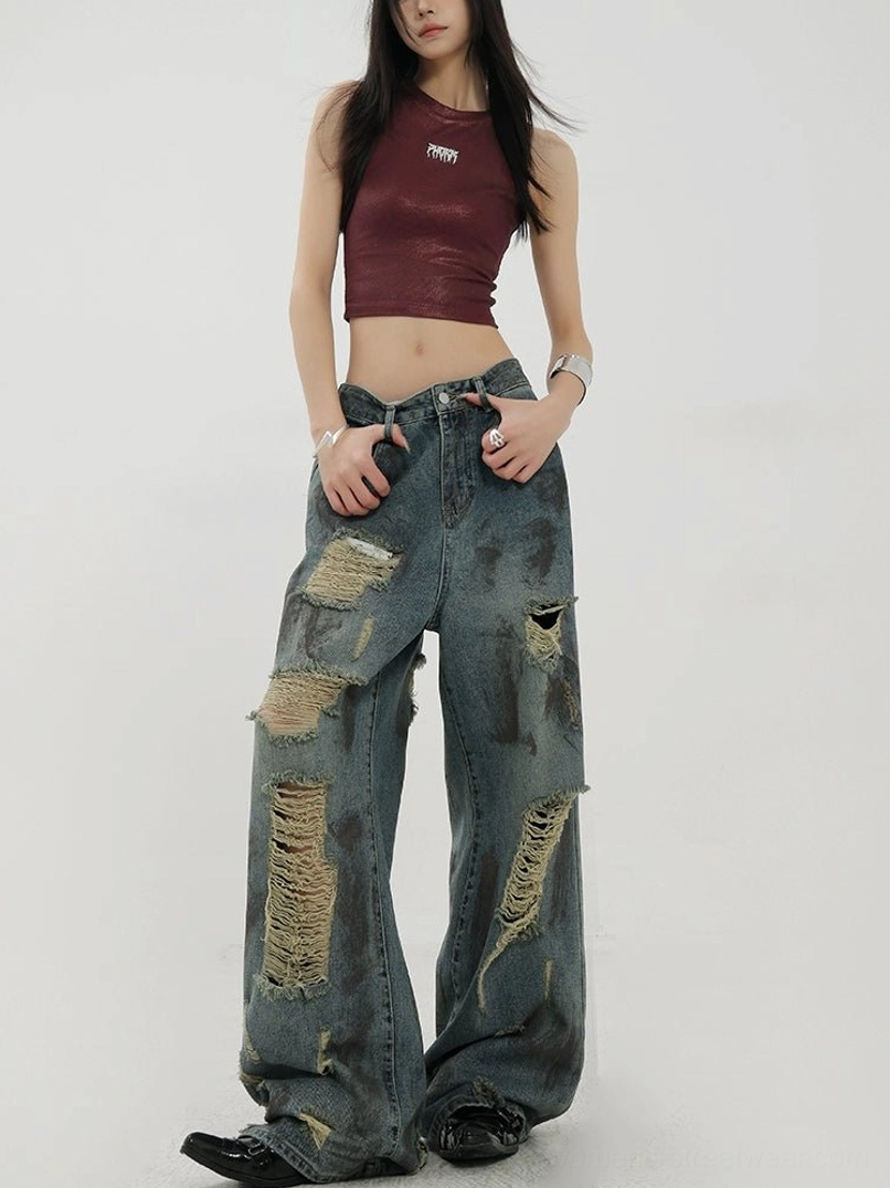 Three-quarter front view of relaxed blue distressed wide-leg jeans with dirty faded wash and shredded leg details