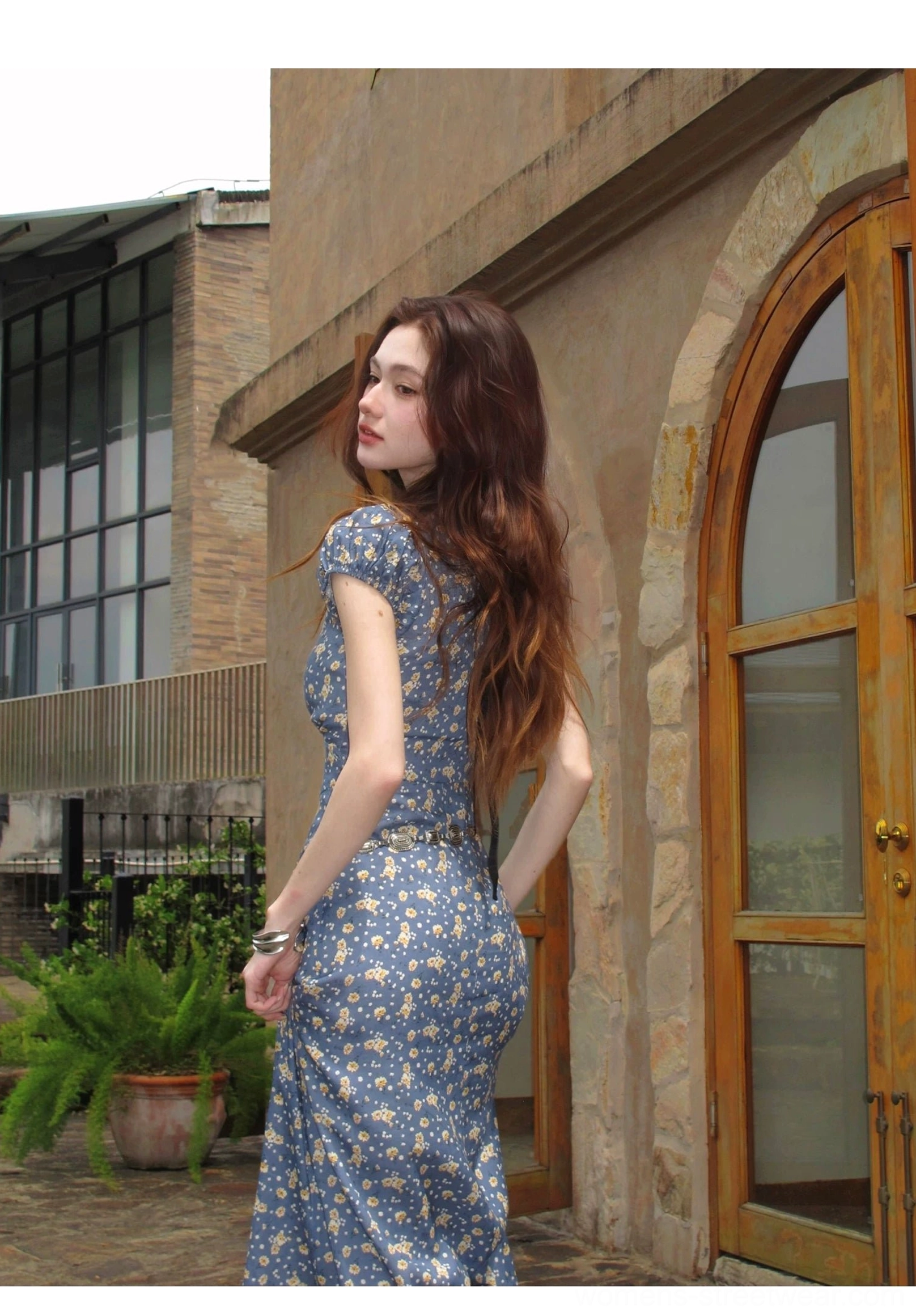 Back three-quarter view of blue ditsy floral open-back maxi dress with short puff sleeves and ribbon detail