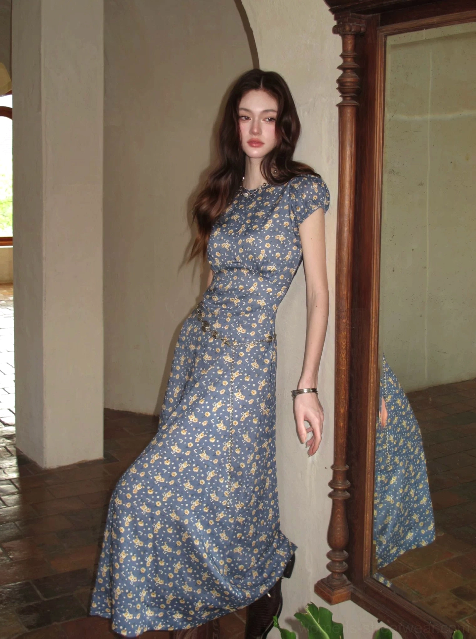 Blue ditsy floral maxi dress with fitted waist and puff cap sleeves shown beside a vintage mirror