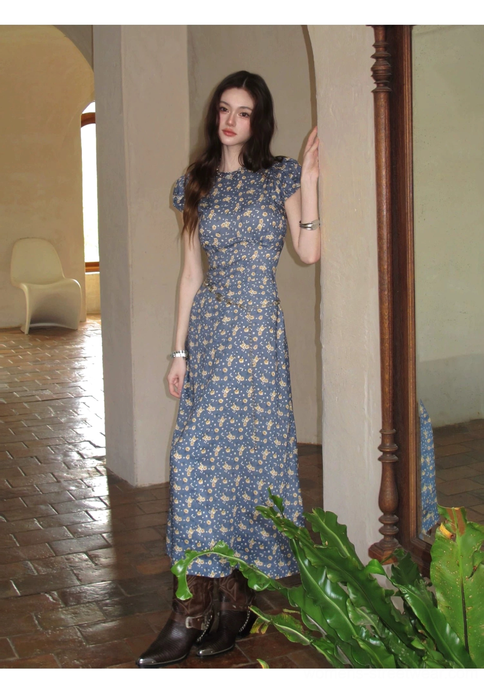 Full-length blue ditsy floral maxi dress with a slim bodice and flowing skirt styled in a vintage corridor