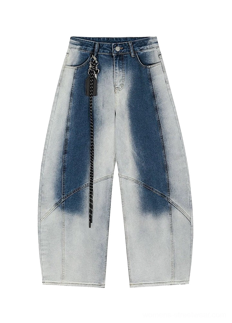 Flat lay front view of blue faded wide-leg denim streetwear pants with curved panel seams, belt loops, button fly, pockets, and attached chain accessory