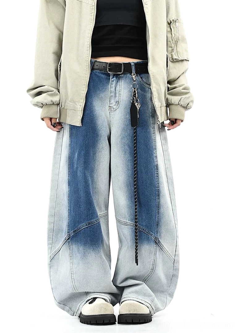 Front full-body view of blue faded wide-leg denim pants showing curved seams, front pockets, waistband details, chain belt, cropped top, and sneakers