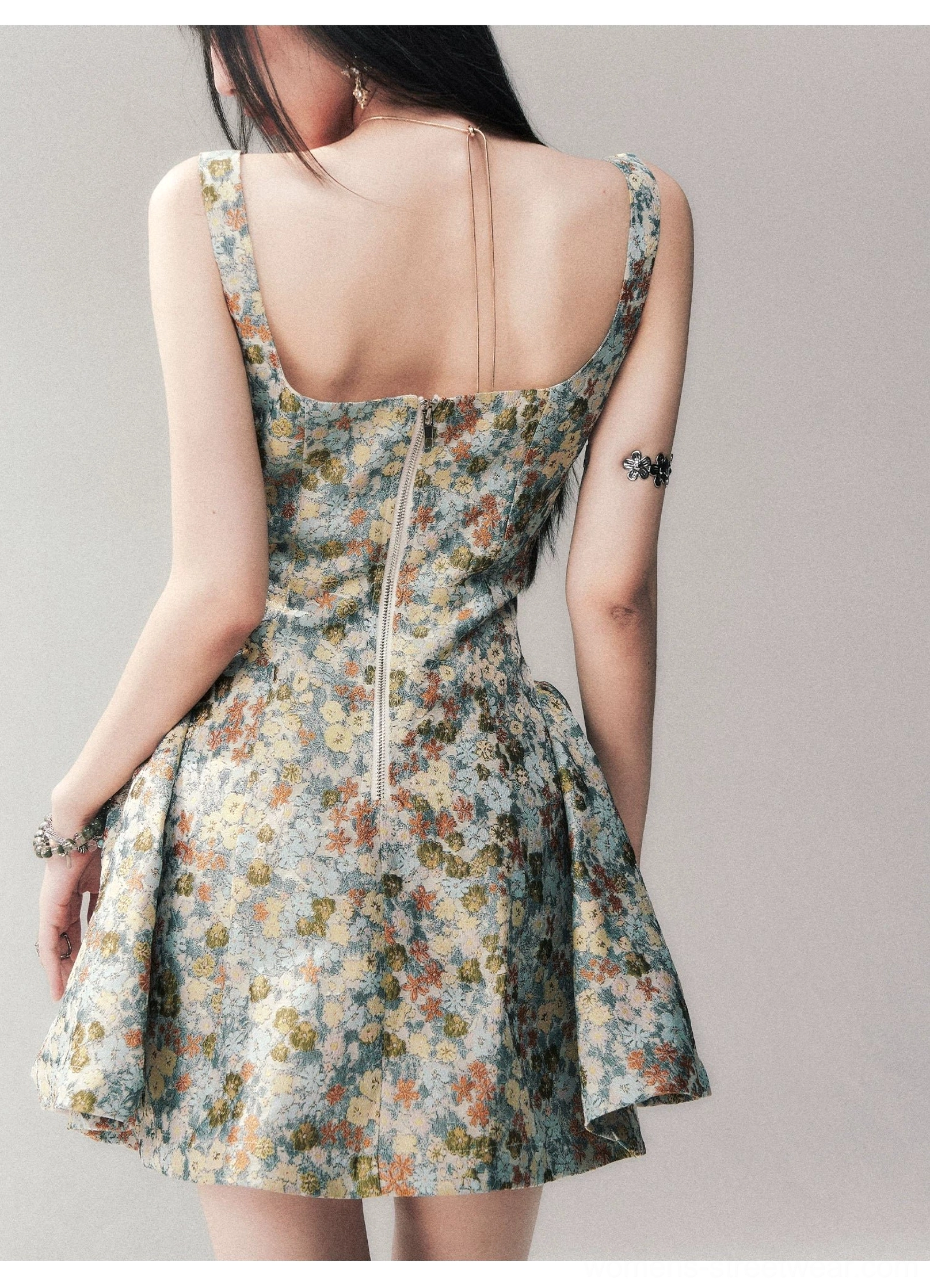 Back view of a blue floral brocade mini dress showing the open-back strap detail, rear zipper closure, fitted bodice, and textured matching jacquard fabric