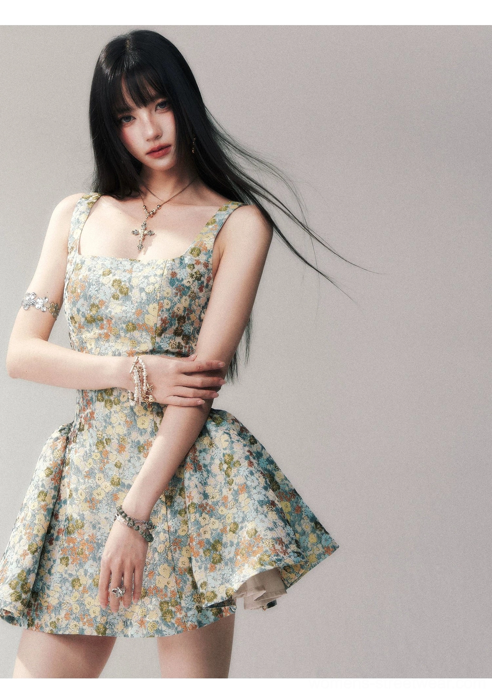 Blue floral fit-and-flare mini dress styled with a cross pendant necklace and crystal bracelets, featuring a square neckline, structured waist, and vintage brocade texture