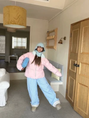 Blue gingham fleece-lined streetwear pants worn with a pink padded coat and snow boots in a cozy winter outfit