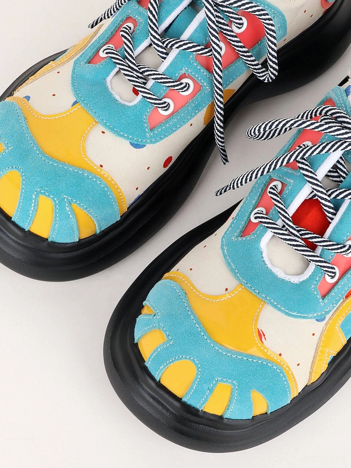 Overhead close-up of blue graffiti graphic platform derby shoes showing striped laces, colorful print, and matte black outsole