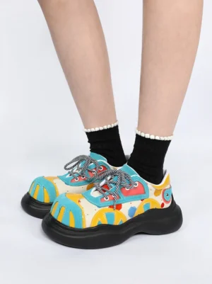 Blue graphic platform derby shoes worn with black frilled crew socks in a front low-angle streetwear styling view