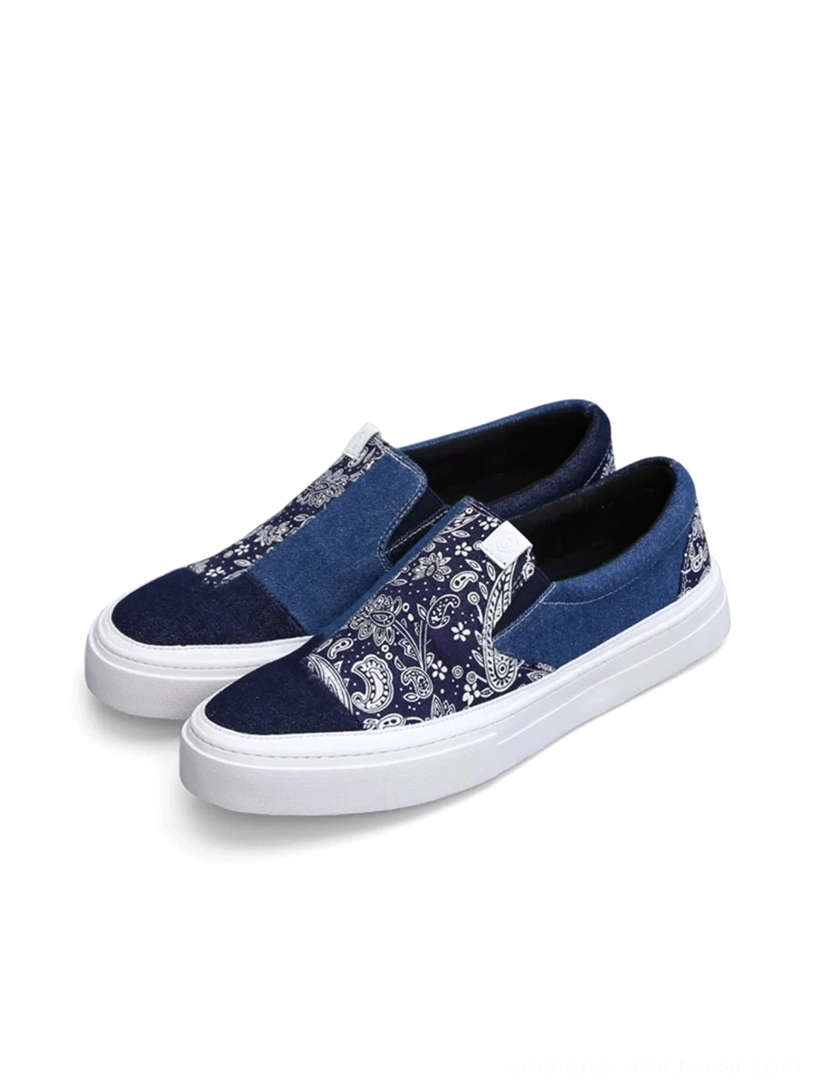Flat lay of two pairs of blue indigo and white paisley patchwork low-top slip-on sneakers showing the full textile design