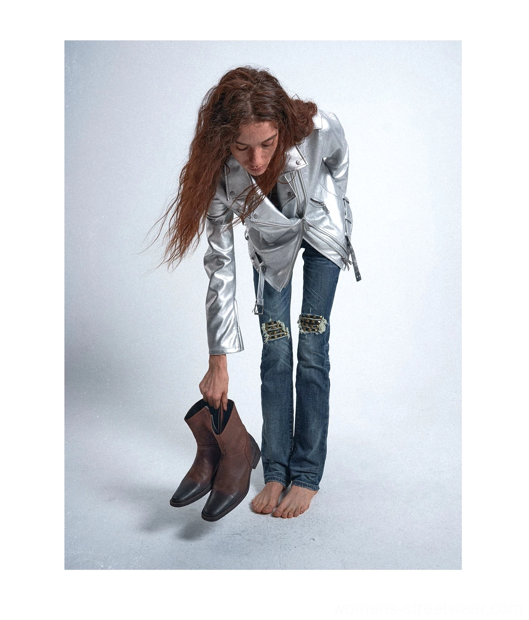 Low-angle front view of blue knee-ripped slim-fit jeans showing the distressed patch details and flexible tapered denim silhouette