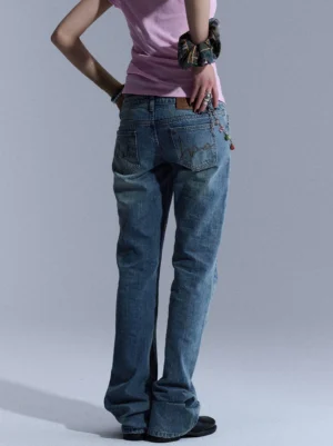 Back partial view of blue vintage wash low-rise flare jeans with decorative waist chain and fabric accents styled for streetwear