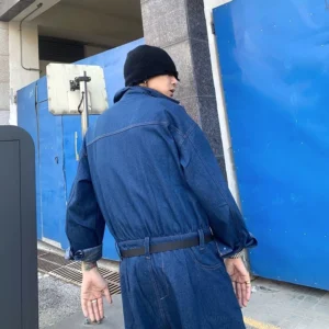Blue oversized denim workwear jumpsuit back view showing relaxed coverall silhouette and matching waist belt